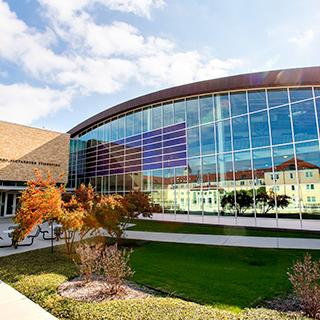 An exterior of the TCU Campus Rec center; other campus buildings are reflected in its shiny surface.